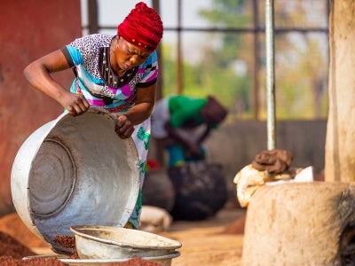 Woman in colorful dress pouring something from a large bowl