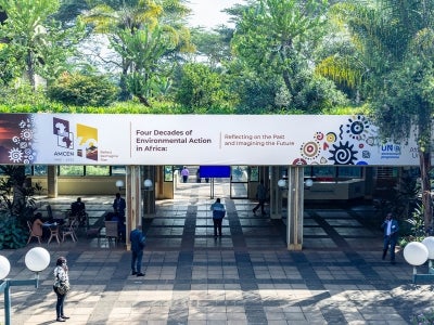 Sign for AMCEN conference in Nairobi, Kenya surrounded by trees