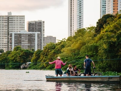 Man pulls people across a river on a boat