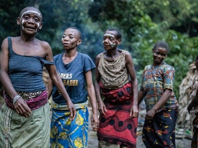 Indigenous Mbuti women dance after sunset in their hunting camp deep inside the Okapi Wildlife Reserve, Democratic Republic of Congo